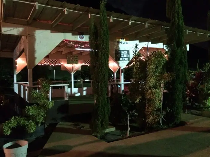 Tall cypress trees and lattice trim glowing at night outside the pavilion