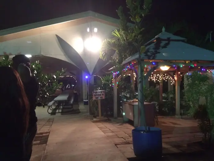 Stone paver courtyard and a gazebo wrapped in string lights beside the pavilion entrance at night
