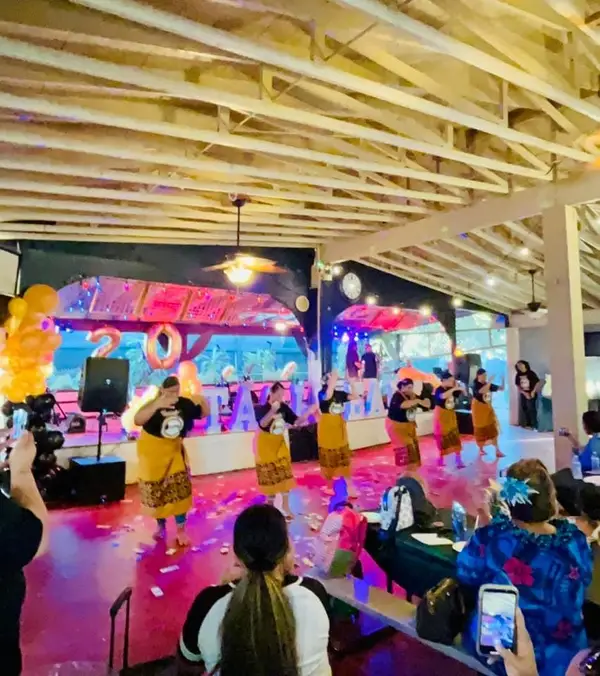 Dancers performing on the dance floor in front of the lit stage while guests film