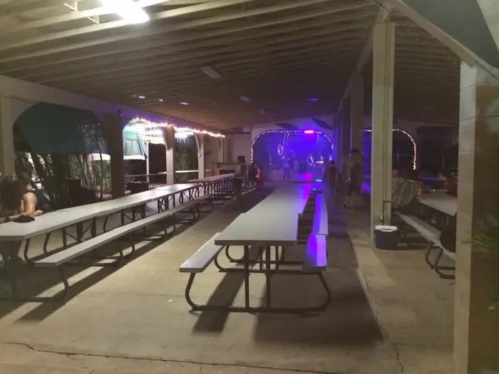 Rows of long tables under the pavilion with the lit stage at the far end